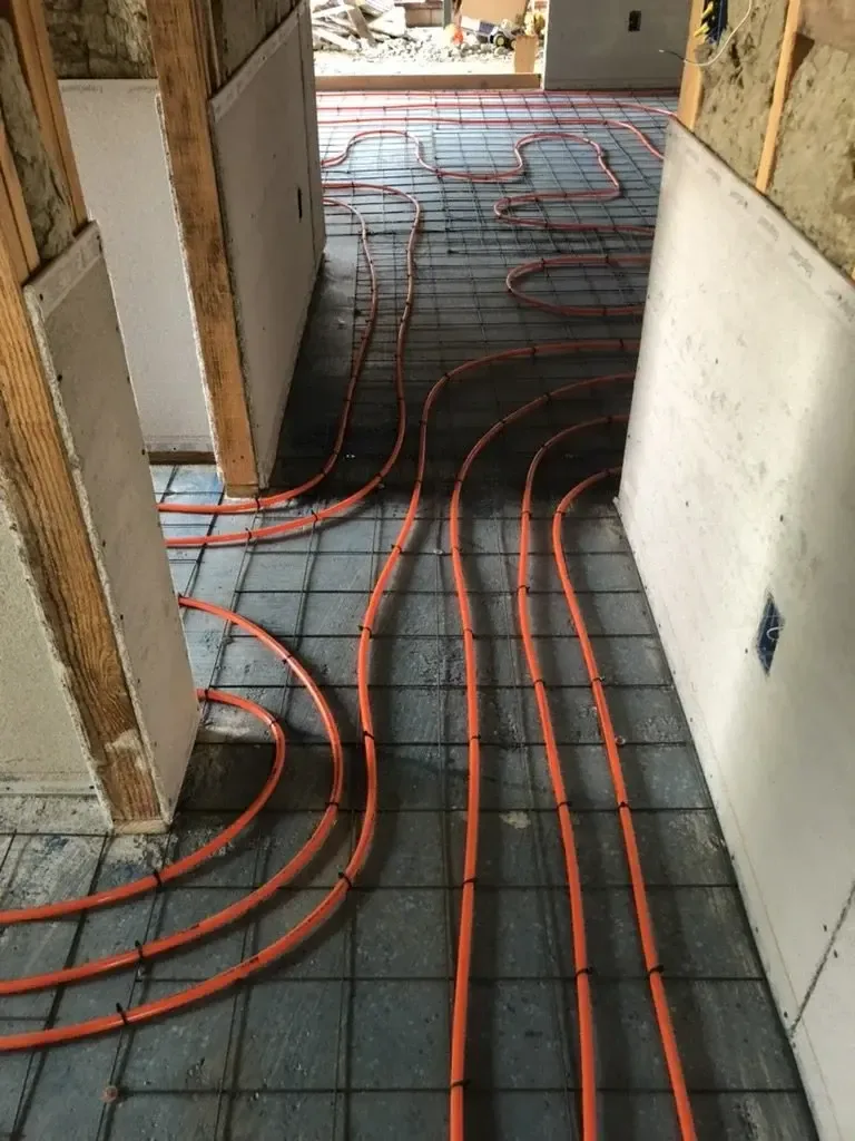 Hydronic radiant heating tubing laid on wire mesh over the subfloor before the slab pour, inside the Walnut project